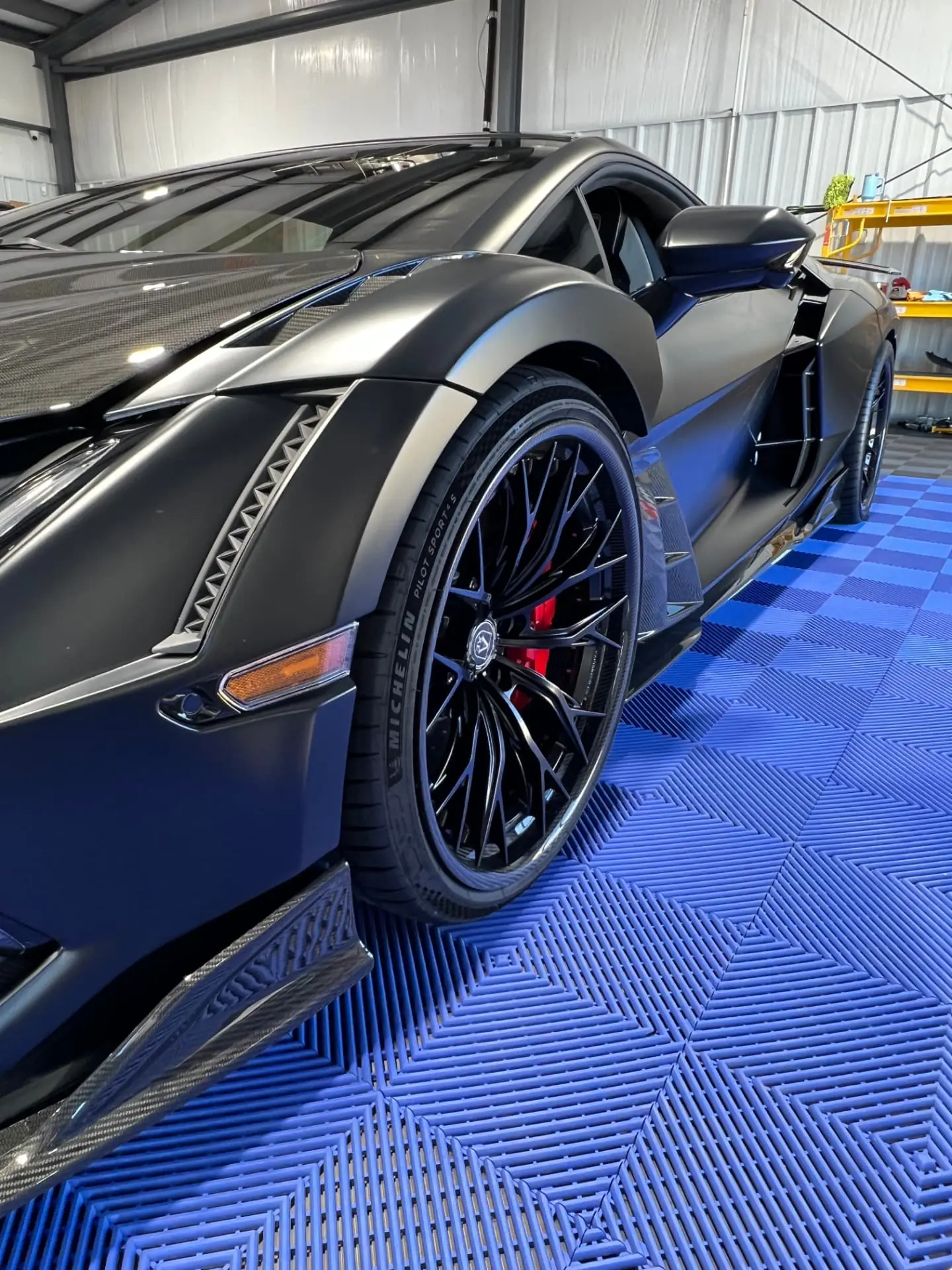 Matte-black Lamborghini with tinted windows inside the Quality Window Tint shop